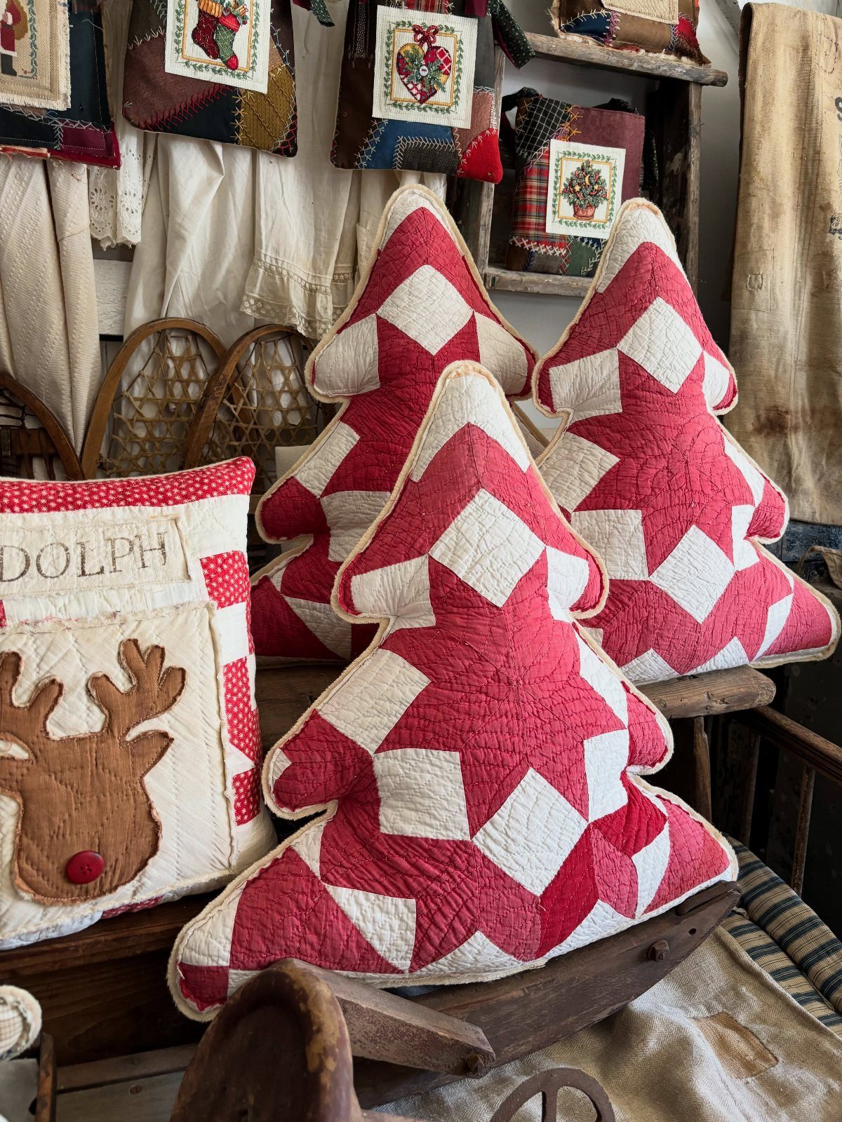 Red and white quilted Christmas tree pillows resting on a vintage wooden sled.