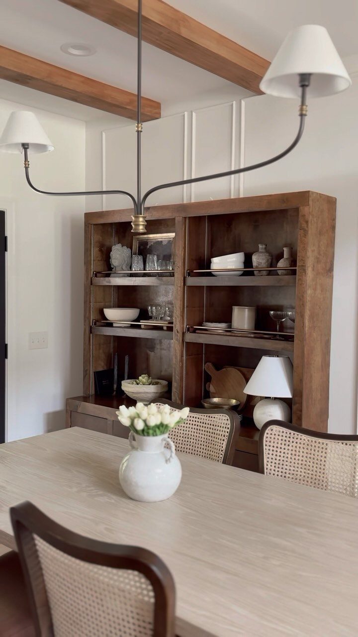 Light wood dining table and chairs with a wooden hutch in neutral tones.