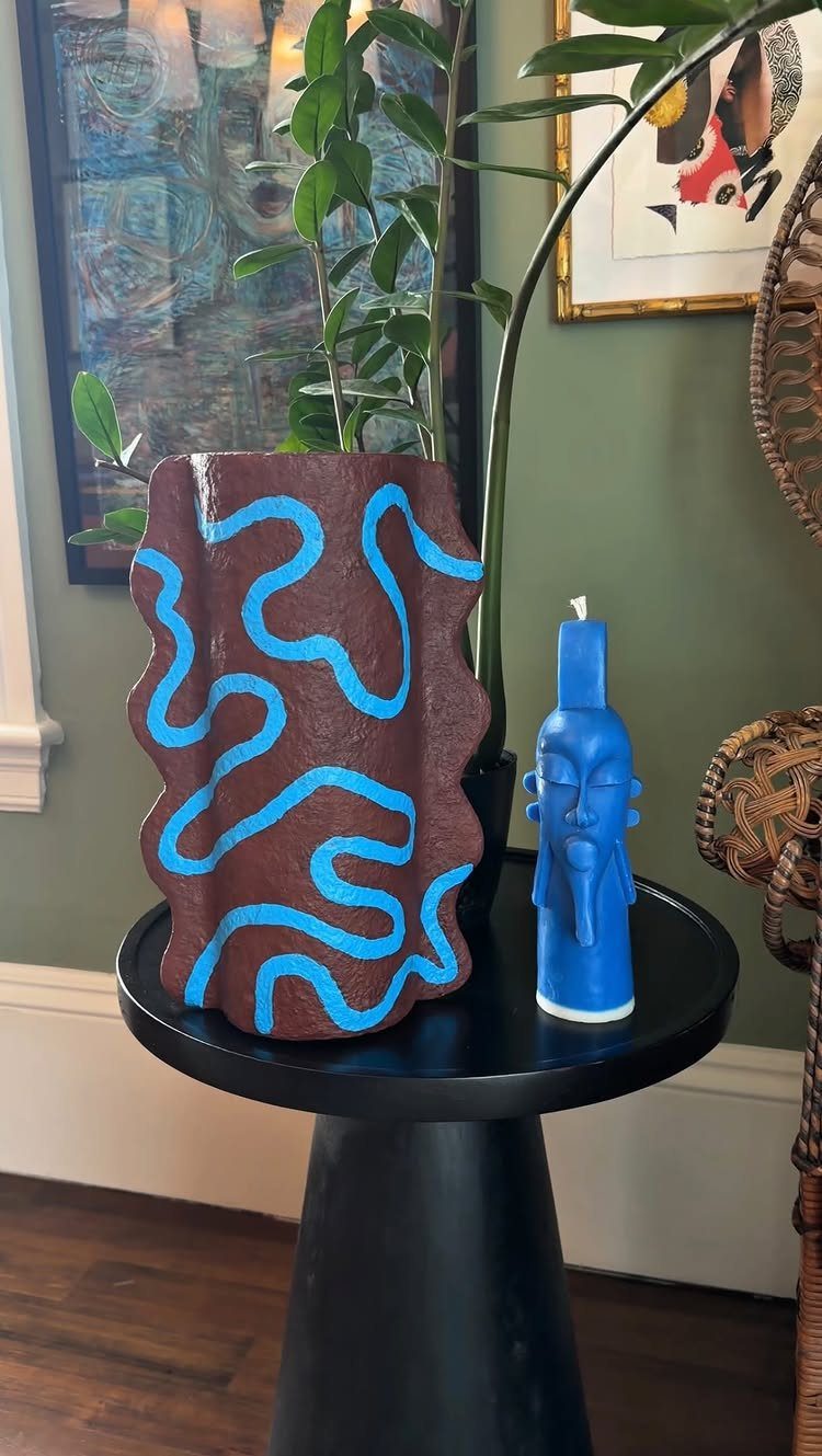 Brown ceramic vase with blue wavy patterns and a blue head-shaped candle.