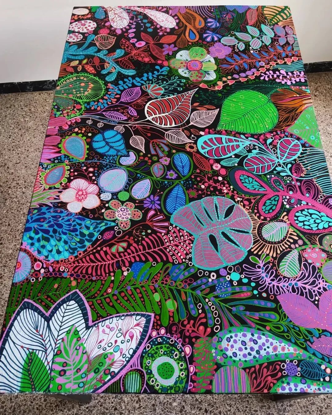 Painted dining room table featuring a colorful, psychedelic tropical leaf and flower pattern.