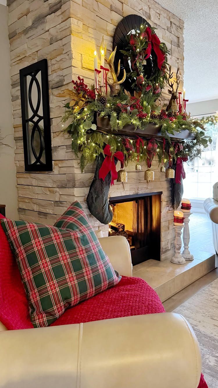 Stone fireplace mantel decorated with green garlands, red bows, and festive berries.