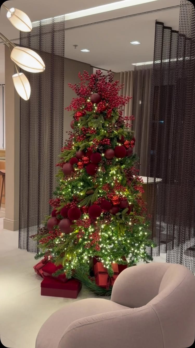 Christmas tree with red ornaments and lights in a modern living room setting