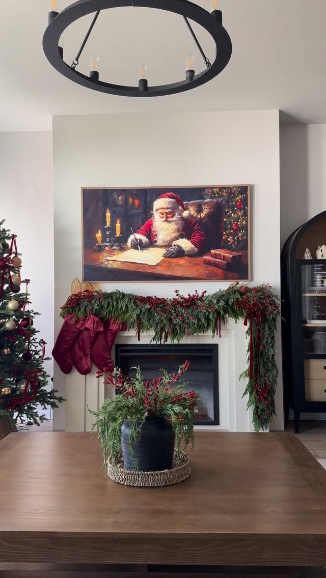 Fireplace mantel decorated with evergreen garland, red stockings, and Santa Claus artwork.