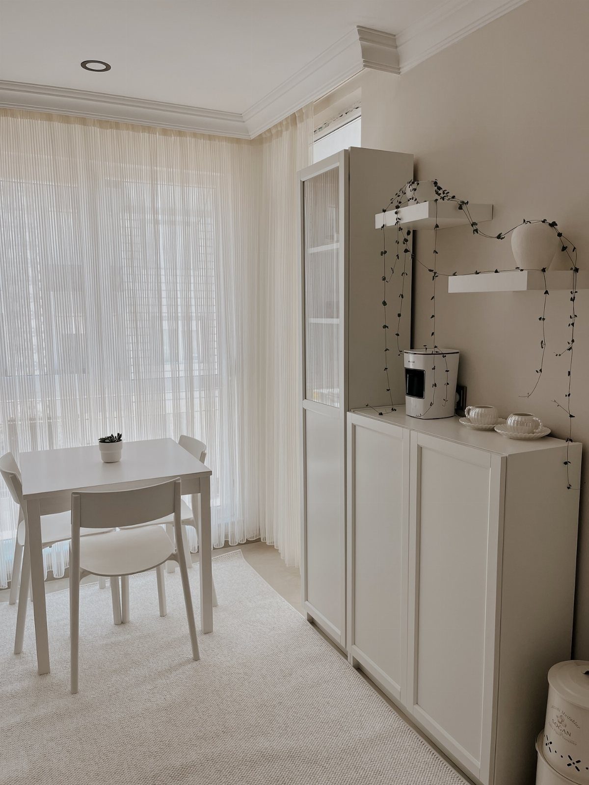 White breakfast table and chairs next to a white cabinet in a bright room