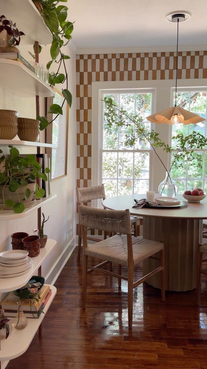 Round breakfast table with woven chairs and a conical pendant light hanging above.