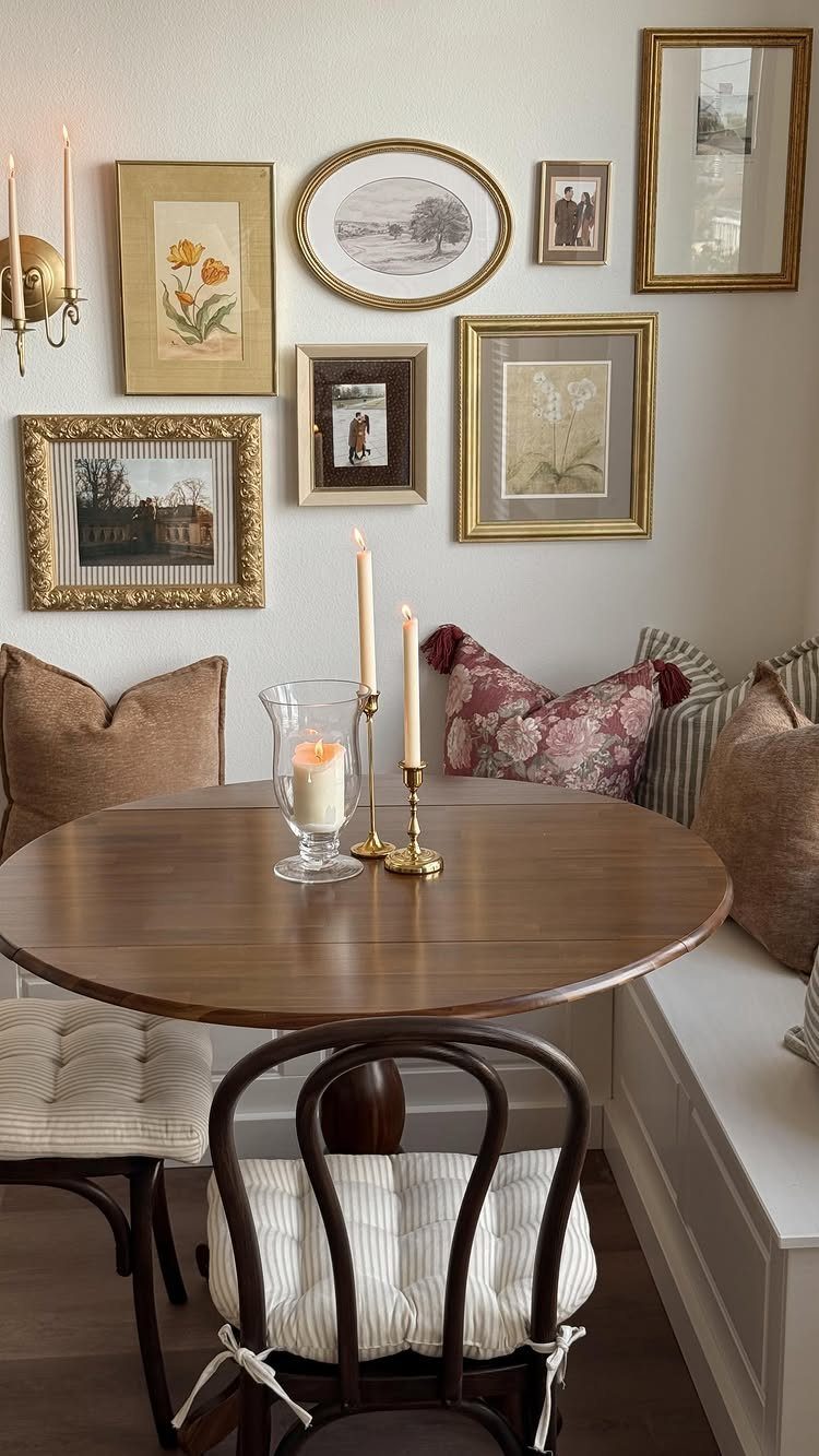 Round wooden table in a breakfast nook with built-in bench and gallery wall.