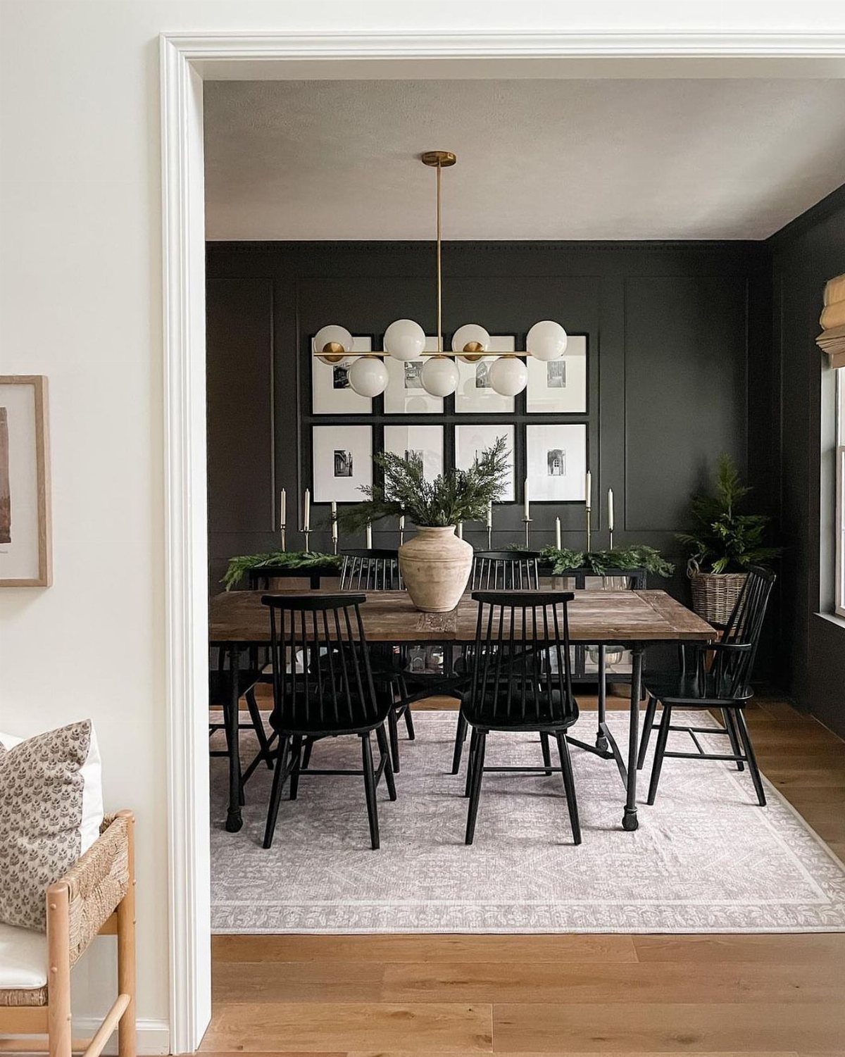 Wooden dining table and black chairs centered on a light patterned area rug.