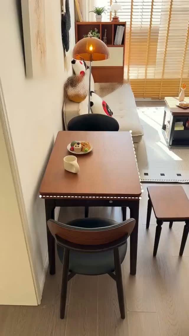 Small wooden dining table with minimal low-profile decor against a white wall.