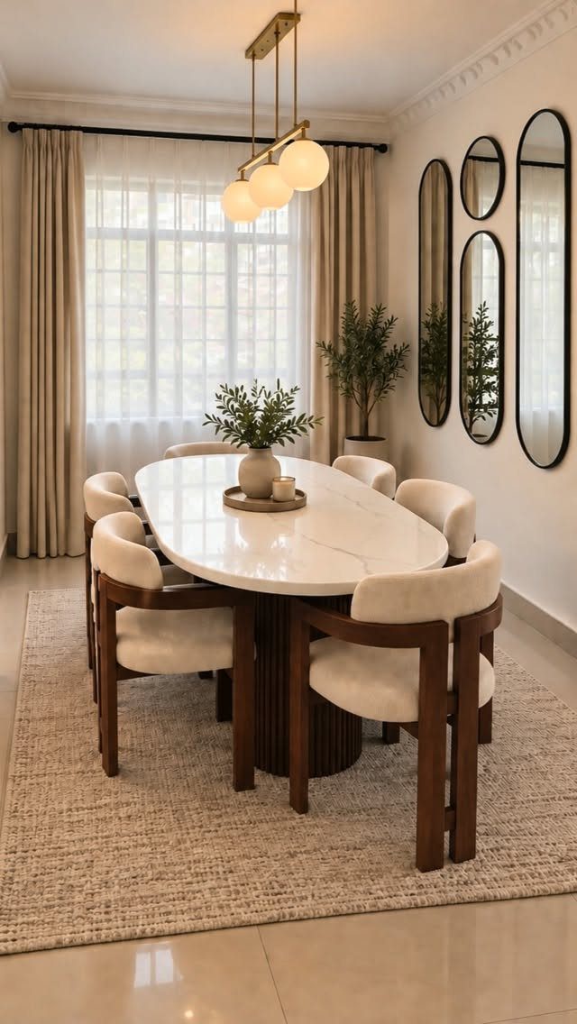 Oval white marble dining table with four oval mirrors hanging on the wall.