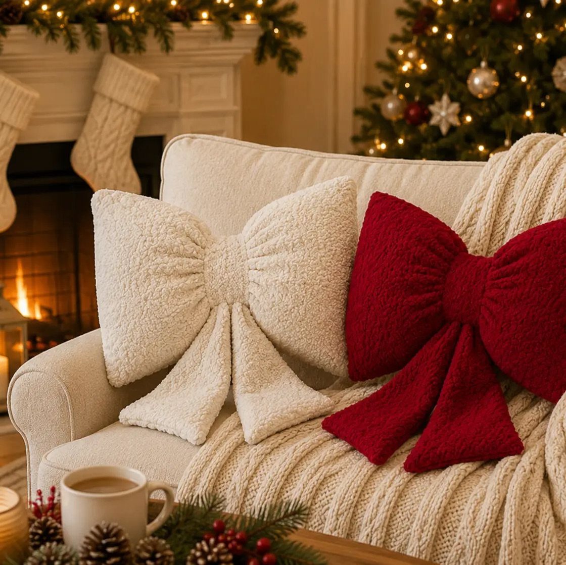 Two bow-shaped Christmas throw pillows in red and cream on a white sofa.