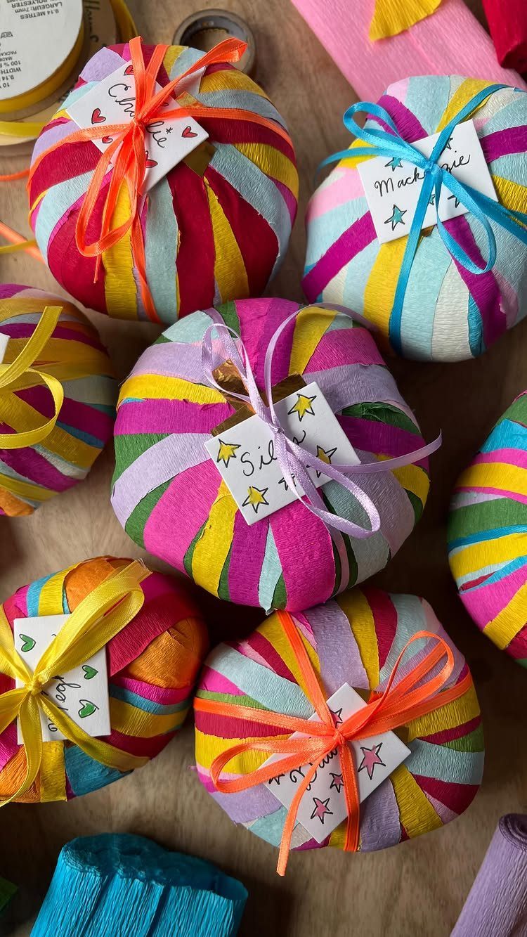 Round gifts wrapped in colorful striped fabric with ribbons and small gift tags.