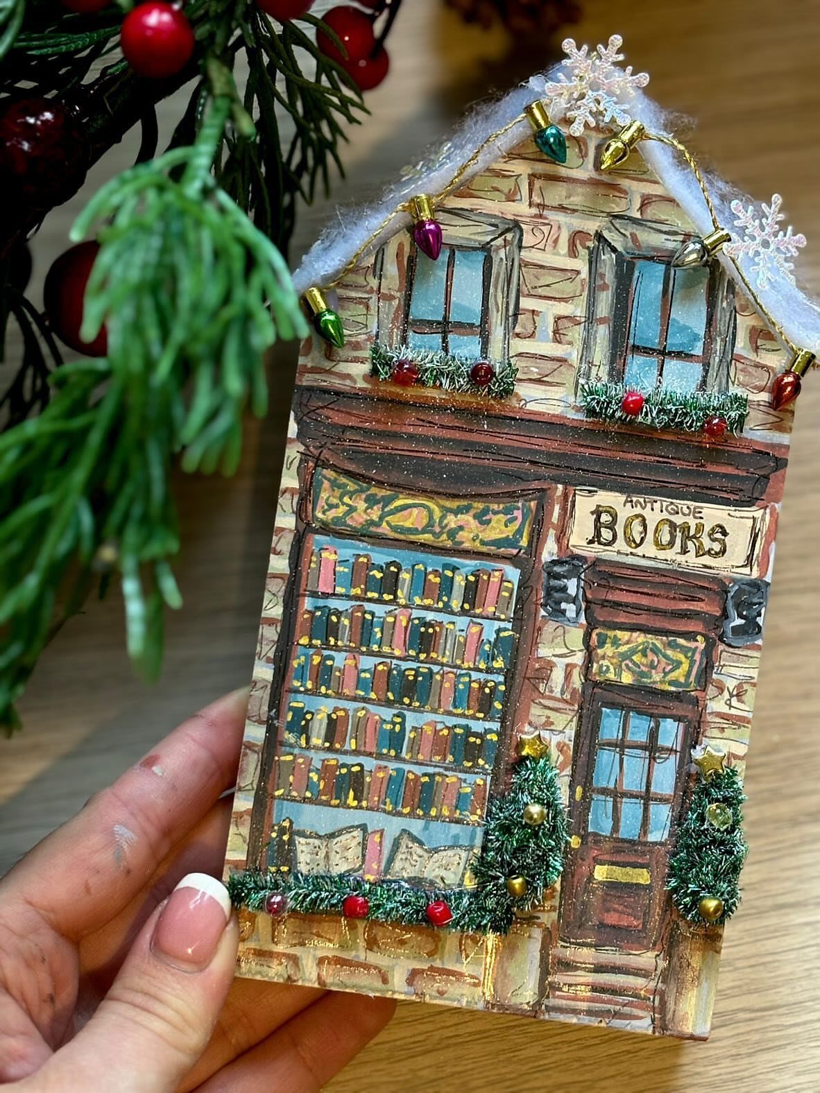 Handmade miniature antique bookstore decorated with tiny Christmas lights and faux snow.
