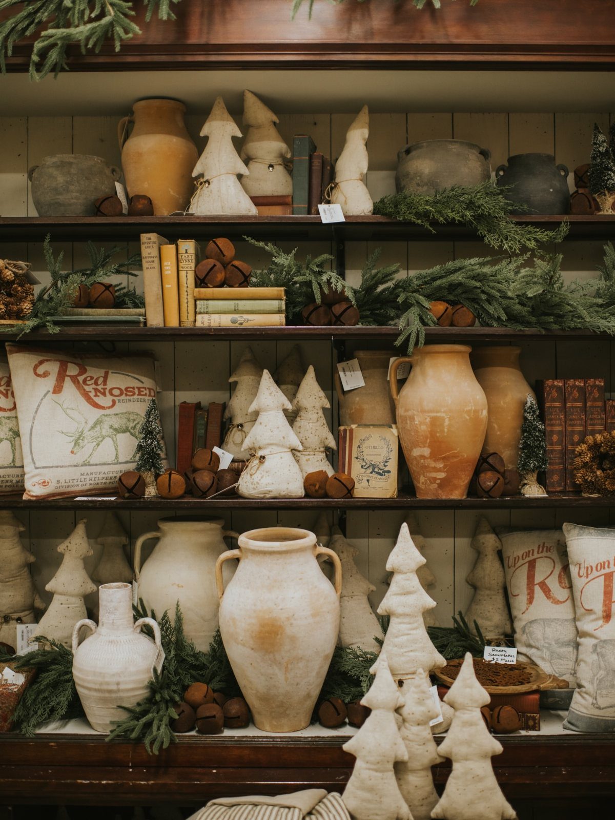 Rustic Christmas decorations with ceramic trees and terracotta vases on wooden shelves.