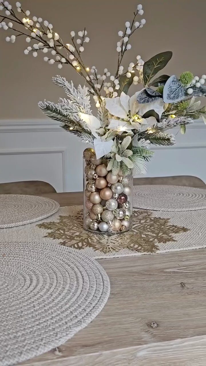 Festive centerpiece with white flowers and gold ornaments on a wooden dining table