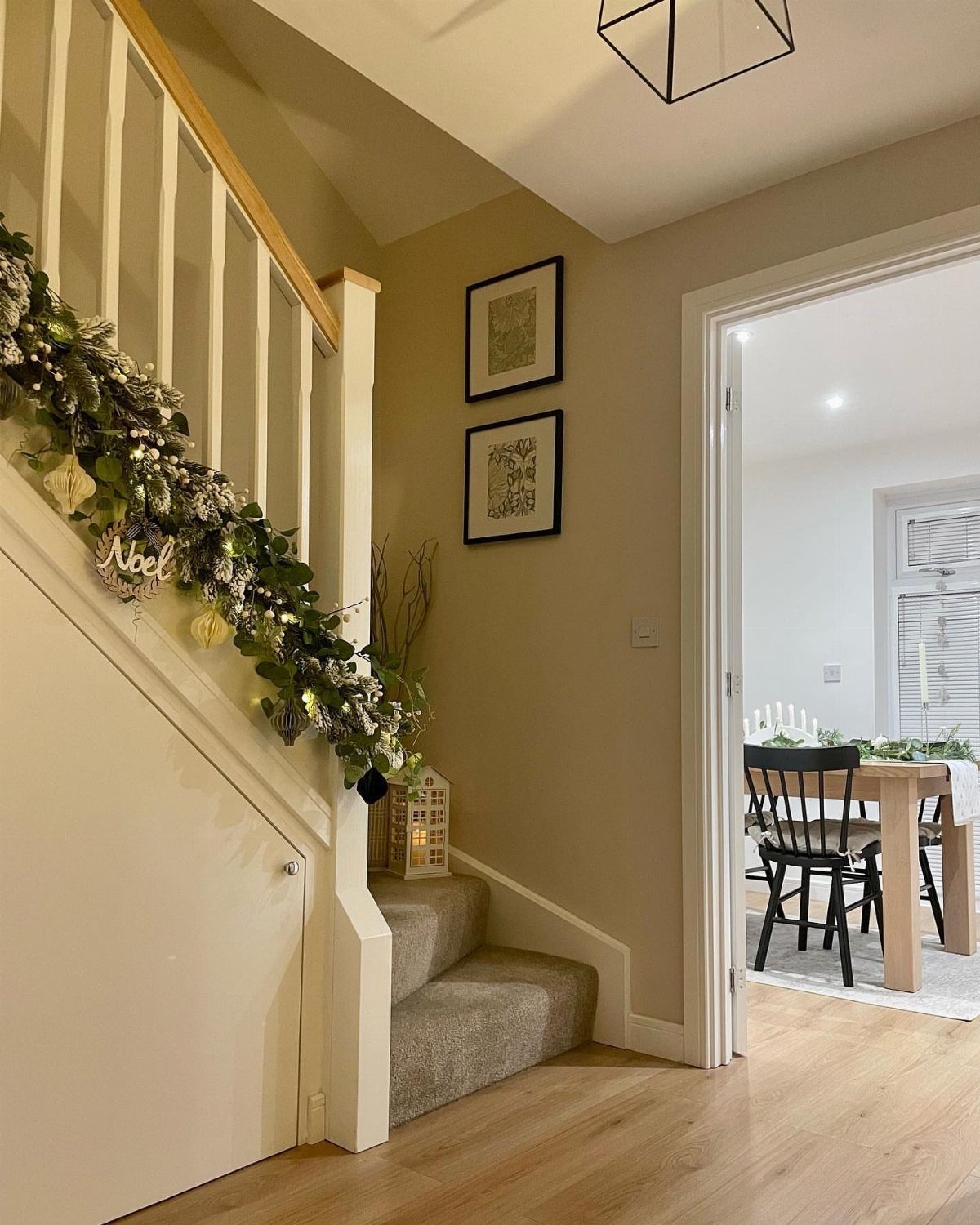 Festive green garland with white ornaments draped along a white staircase banister.