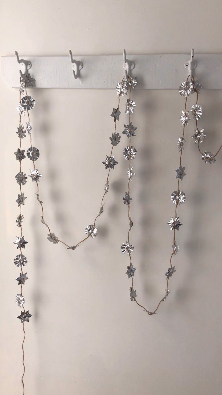 Silver star garland hanging from a white wall rack against a white wall