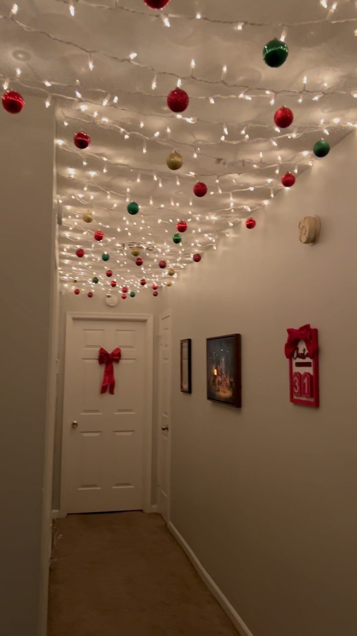 Christmas lights and colorful ornaments hanging from the ceiling of a narrow hallway
