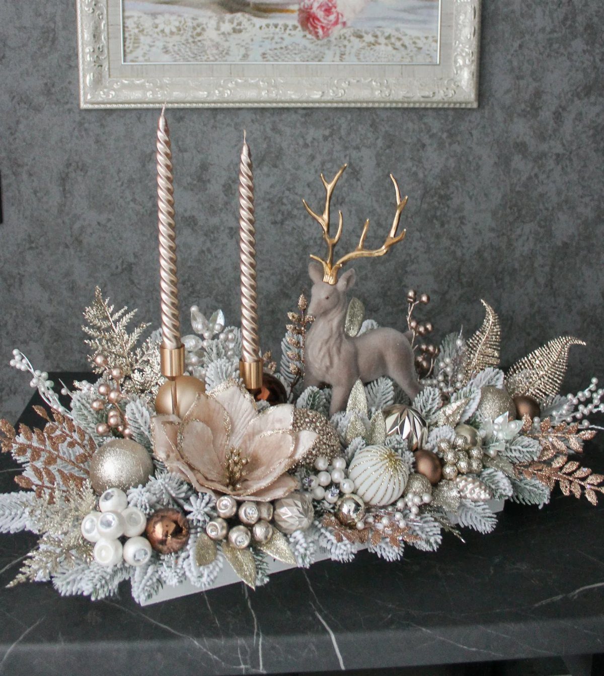 Festive Christmas table centerpiece with gold candles, silver ornaments, and a deer figurine.
