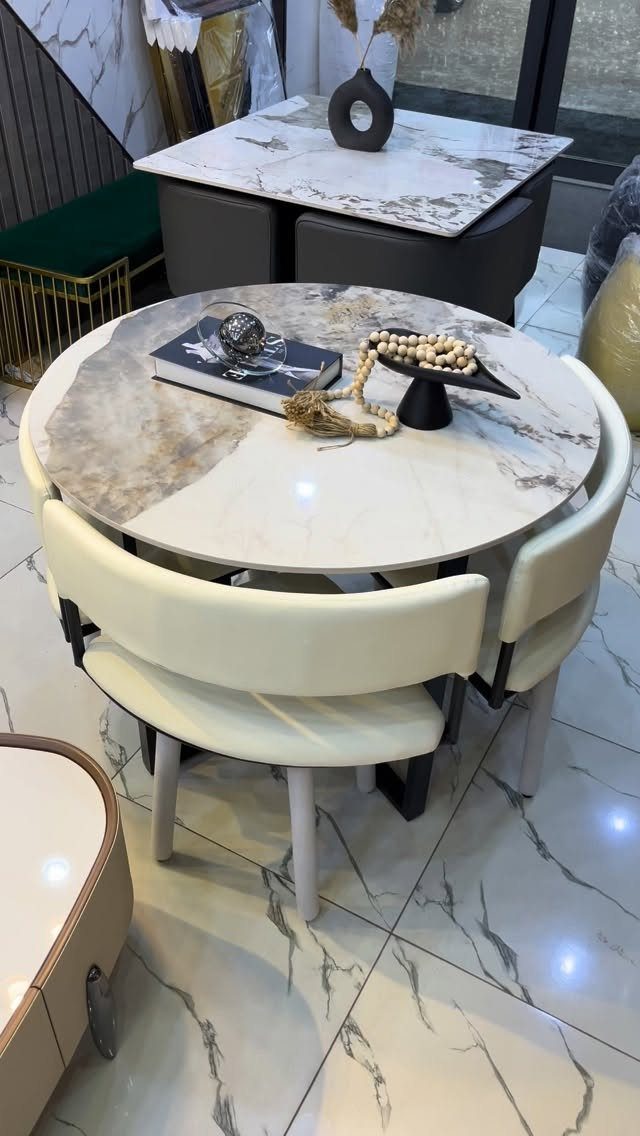 Round marble mini dining table with two cream chairs in a modern room