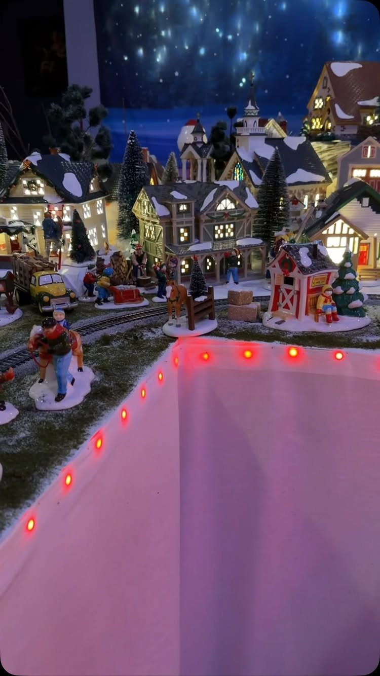 Miniature Christmas village with snow-covered houses and figures under a starry night sky