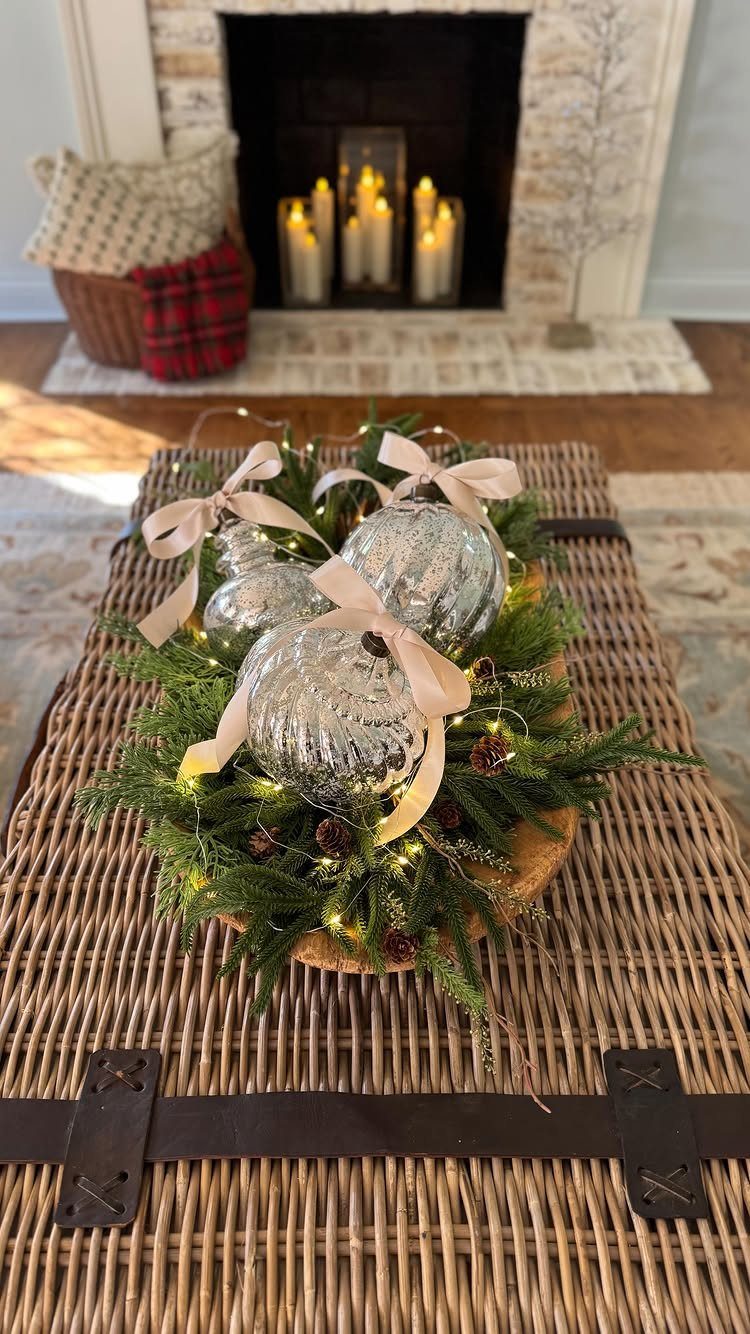 Mercury glass ornaments with bows in a pine branch centerpiece on wicker table