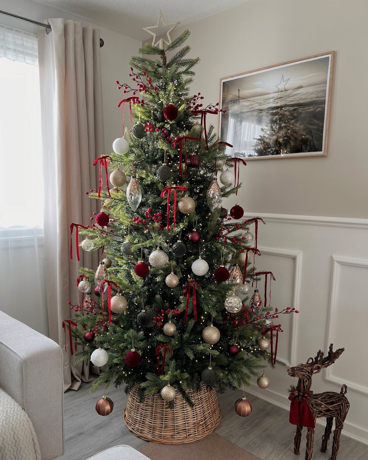 Decorated Christmas tree with red ribbons and ornaments in a wicker basket.