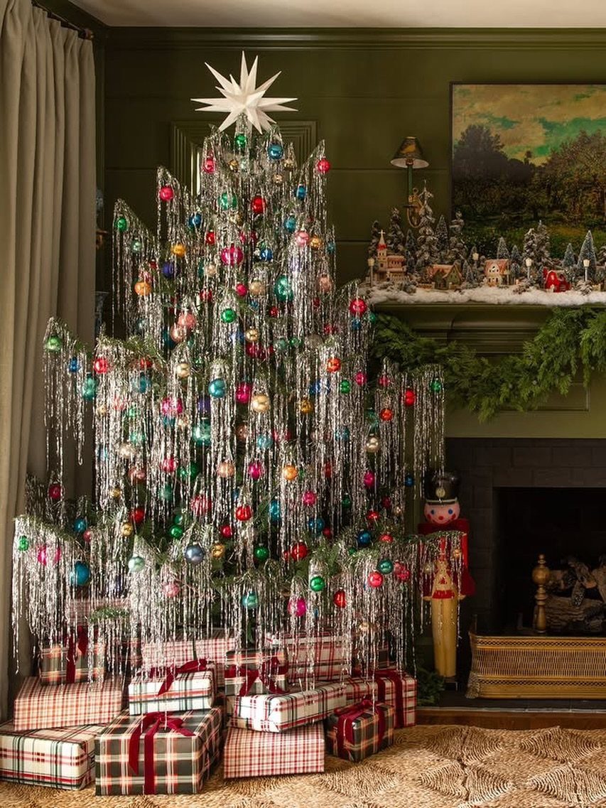 Decorated Christmas tree with silver tinsel garlands and colorful ornaments in a living room