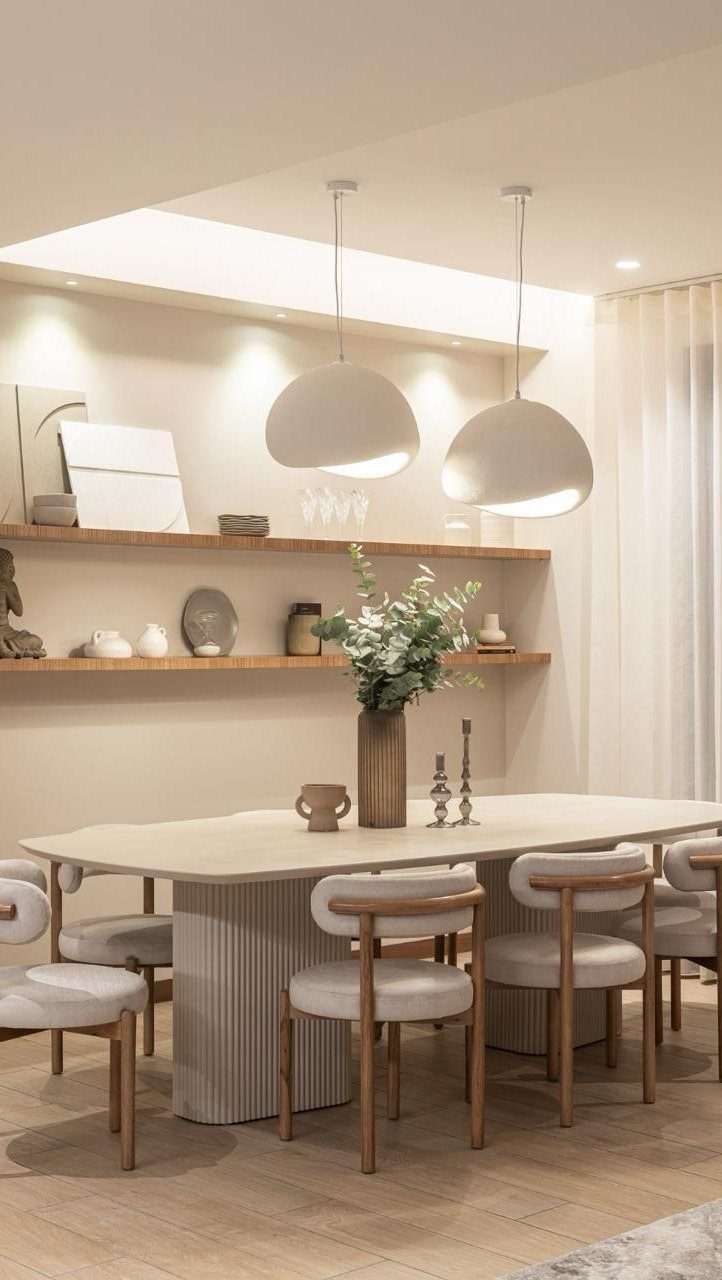 Oval dining table with curved chairs and symmetrical white dome pendant lights.