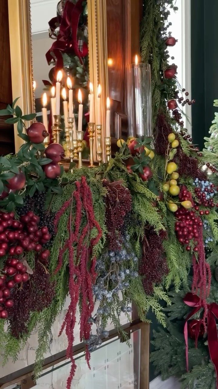 Victorian style Christmas mantel with gold candelabras, lit candles, and lush red greenery.