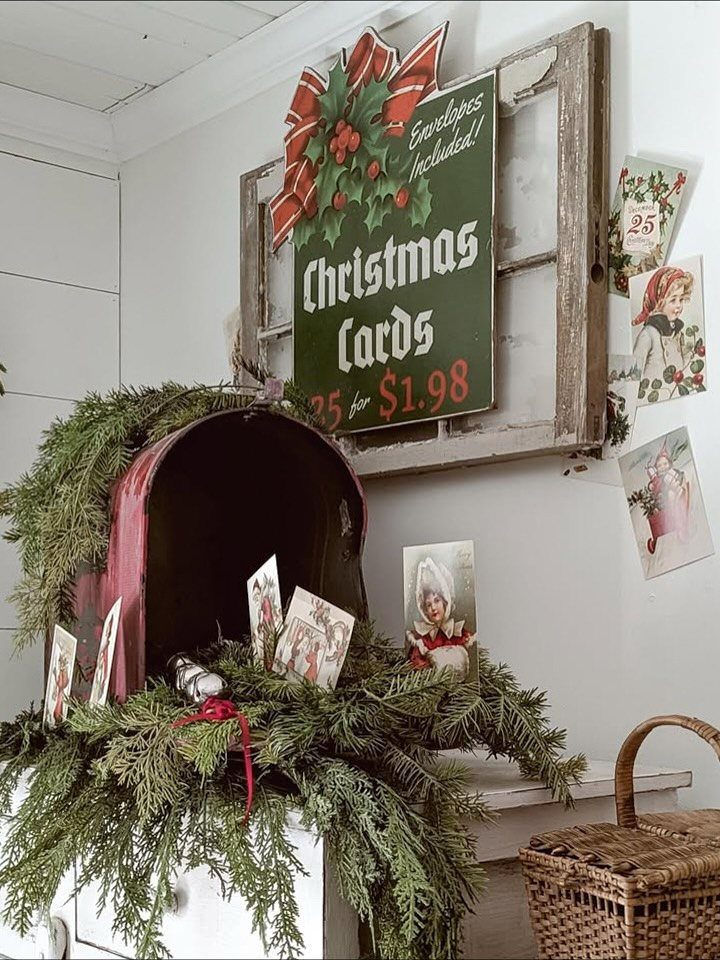 Vintage red mailbox decorated with evergreen branches and antique Christmas postcards.