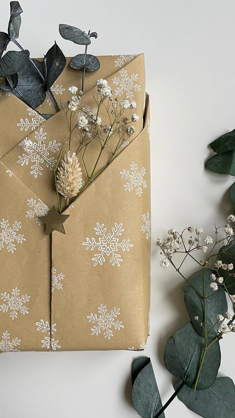 Gift wrapped in brown snowflake paper with a pinecone and eucalyptus leaves.