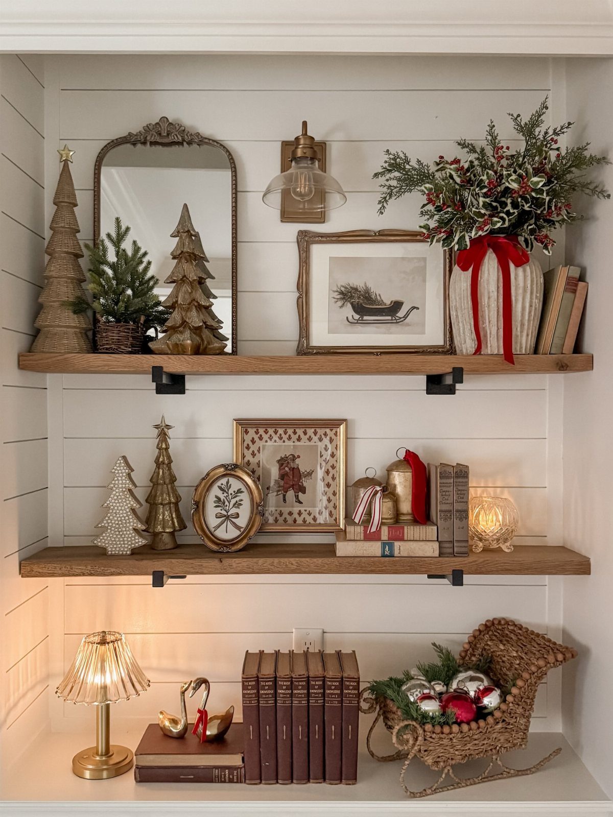Wooden shelves decorated with vintage Christmas ornaments, bottle brush trees, and old books.