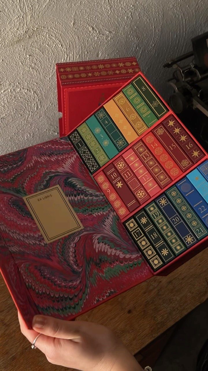 Red book-style advent calendar with colorful numbered faux book spines and marbled lining.