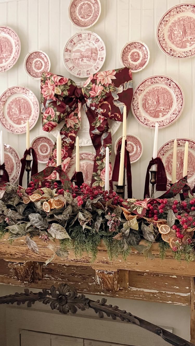 Rustic mantel with dried fruit garland, vintage plates, and a large floral bow.