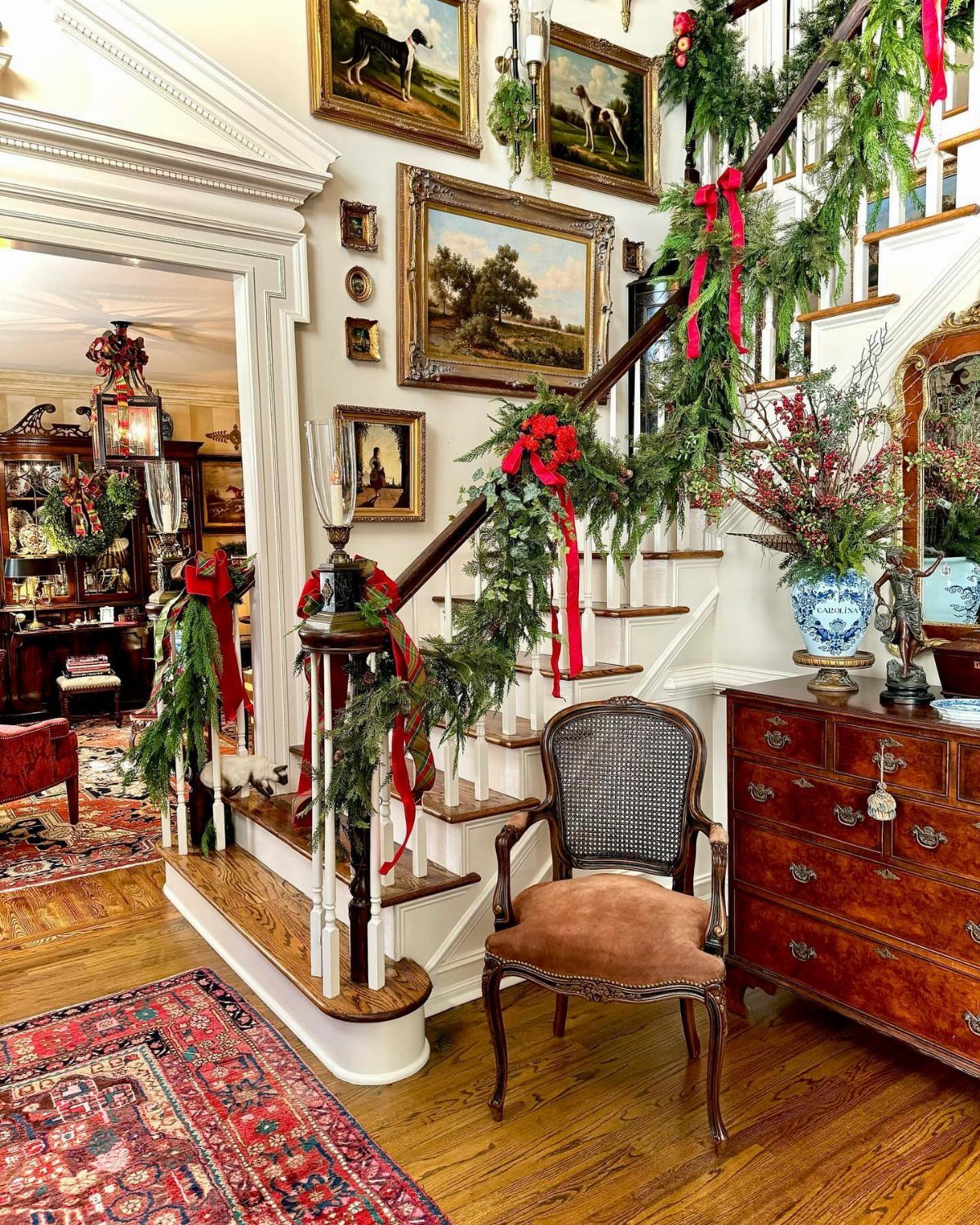 Evergreen garlands with red bows decorating a wooden staircase in a vintage home.