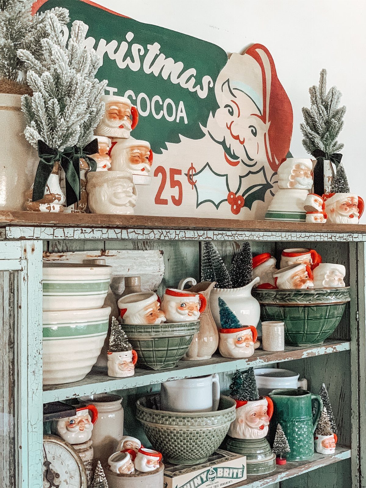 Santa Claus face mugs and green bowls on a vintage blue wooden shelf