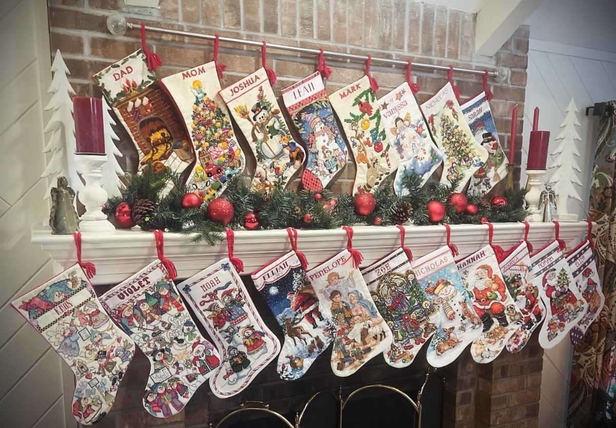 Illustrated Christmas stockings with names hanging from a decorated white fireplace mantel.