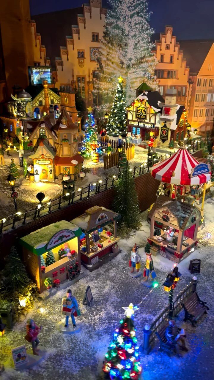 Miniature Christmas village with glowing houses, market stalls, and decorated tiny trees.