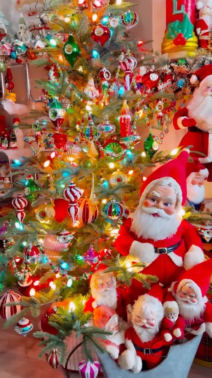 Decorated Christmas tree with vintage ornaments and lights next to Santa Claus figurines