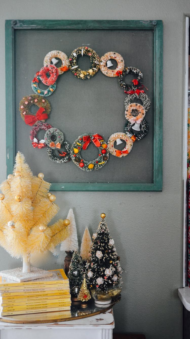 Small colorful vintage wreaths arranged in a circle above bottle brush Christmas trees.
