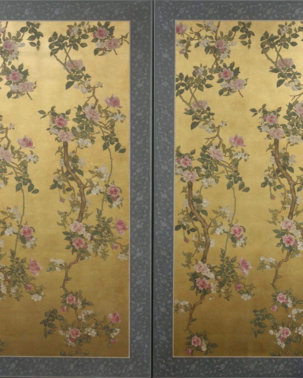 Two gold chinoiserie panels with pink floral branches and grey textured frames.