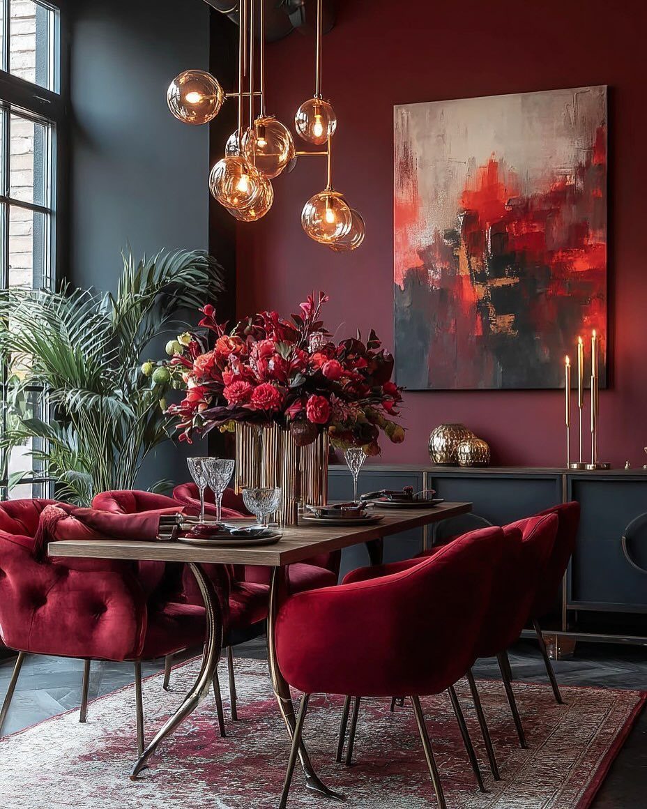 Burgundy dining room with red velvet chairs, gold lighting, and abstract wall art.